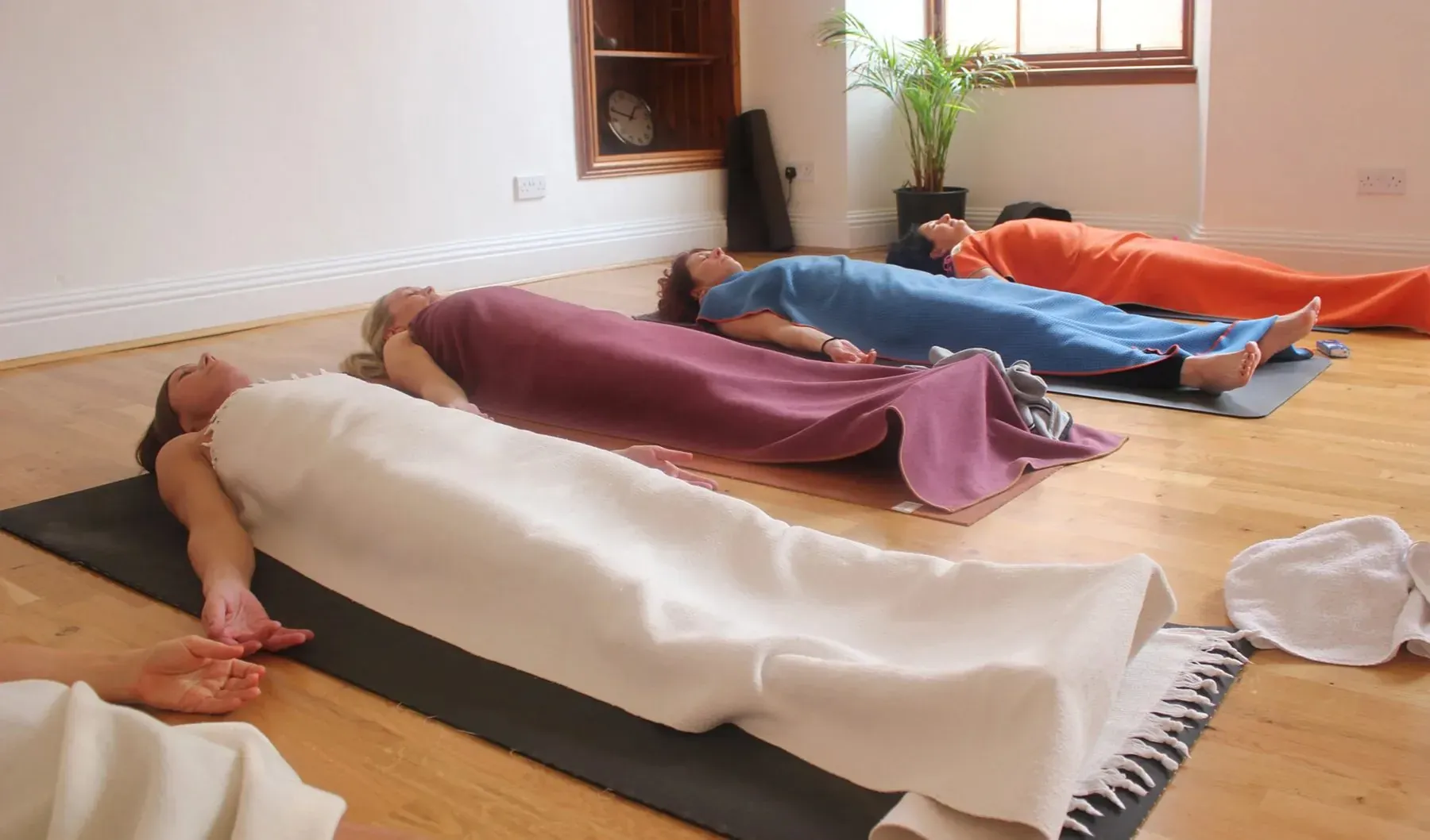 Účastníci relaxace leží na podložkách přikrytí dekami
